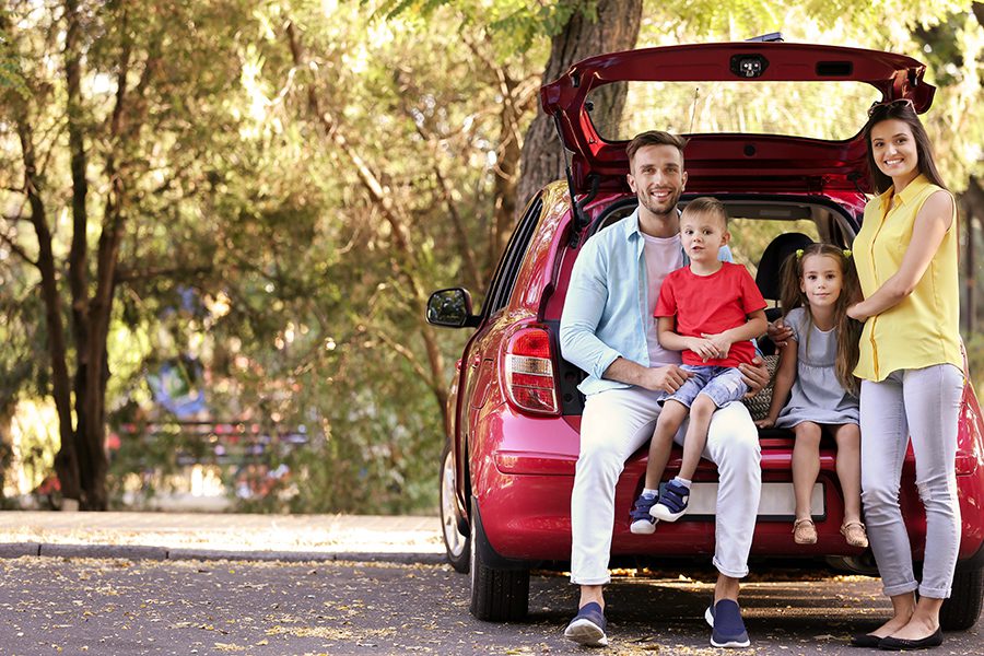 Personalized Insurance - Family with Kids Sitting in Car Trunk Parked Along the Street of a Suburban Neighborhood